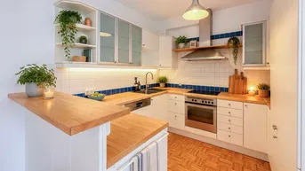 Helle Küche mit Holztheke, weißen Schränken und blauen Akzentfliesen, ausgestattet mit modernen Geräten.