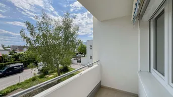 Heller Balkon mit Blick auf die Straße und umliegende Gebäude, ideal für entspannte Stunden im Freien.