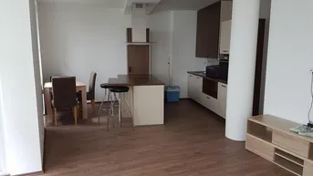 Offener Wohn- und Essbereich mit integrierter Küche, Frühstücksbar und Laminatboden.