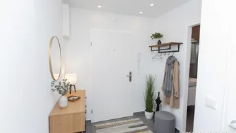 Heller Eingangsbereich mit moderner Einrichtung, Spiegel, Garderobe und Fliesenboden.