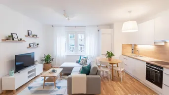 Helles, modern eingerichtetes Wohn-Esszimmer mit offener Küche und Parkettboden.