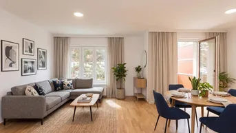 Helles Wohn- und Esszimmer mit Parkettboden, modernem Sofa und Zugang zum Balkon.