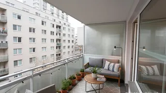 Möblierter Balkon mit Blick auf die umliegenden Wohngebäude und gemütlicher Beleuchtung.