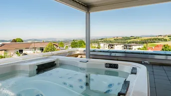Luxuriöser Whirlpool auf der Dachterrasse mit weitem Blick über die grüne Landschaft.