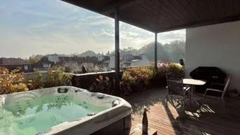 Geräumige Dachterrasse mit Whirlpool, Holzboden und weitem Blick über die Stadt.