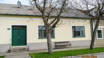 Traditionelles Einfamilienhaus mit grüner Eingangstür und kleinen Fenstern an der Vorderseite.