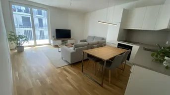 Helles, offenes Wohn-Esszimmer mit integrierter Küche, Parkettboden und Zugang zum Balkon.