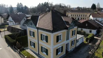 Luftaufnahme des gelben Hauses mit markanter Dachform und umliegender Wohnbebauung.