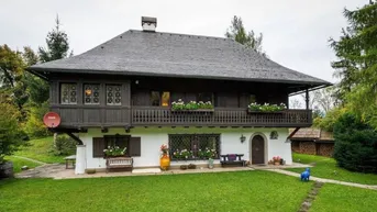 Traditionelles alpenländisches Haus mit Holzbalkonen, weißer Fassade und gepflegtem Vorgarten.