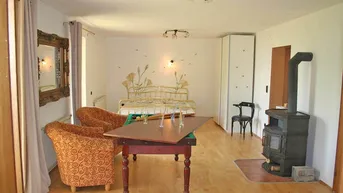 Gemütlicher Wohnbereich mit Holzboden, Kaminofen und floraler Wanddekoration.