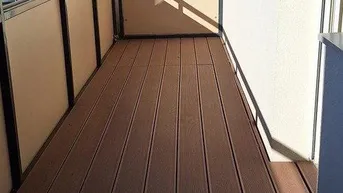 Langer Balkon mit Holzboden und Blick auf die Umgebung.