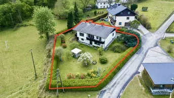 Luftaufnahme eines Hauses mit großem Garten und roter Grundstücksumrandung in ländlicher Umgebung.