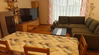 Offener Wohn-Essbereich mit Esstisch, gemütlichem Sofa und einem modernen Holzofen.