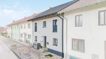 Ansicht der modernen Hausfassade eines Reihenhauses mit gepflastertem Vorgarten und kleinen Balkonen.