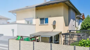 Außenansicht des Hauses mit überdachtem Sitzbereich und Trampolin im Garten.