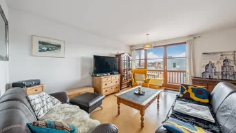 Helles Wohnzimmer mit bequemen Ledersofas, Holzboden und Zugang zu einem Balkon.