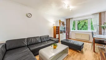 Heller Wohn- und Essbereich mit dunklem Ledersofa, modernem Couchtisch und Blick ins Grüne.