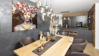 Moderner offener Wohn- und Essbereich mit Holztisch, Designerleuchten und integrierter Küche.