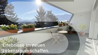 Sonnige Terrasse mit modernem Design, Sitzgelegenheiten und weitem Blick auf die Berge und die Stadt.