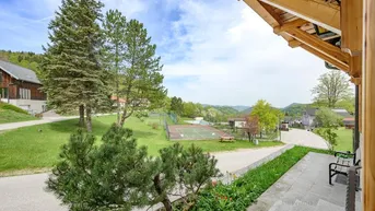 Weitläufiger Blick von der Terrasse auf die umliegende Landschaft und einen Tennisplatz.
