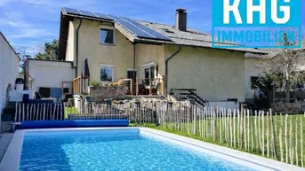 Einfamilienhaus mit privatem Pool, Garten und Solaranlage auf dem Dach unter blauem Himmel.