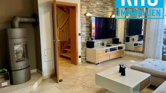 Gemütliches Wohnzimmer mit Kaminofen, Fliesenboden und Zugang zur Holztreppe.