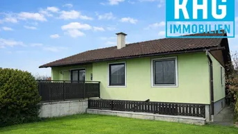 Seitenansicht des Hauses mit grünem Anstrich, braunem Dach und einem kleinen Rasenbereich.