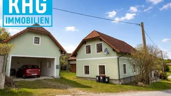 Zwei ländliche Häuser mit hellgrüner Fassade und roten Ziegeldächern in sonniger Umgebung.