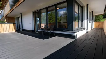 Geräumige Terrasse mit dunklem Holzboden und Blick auf die umliegende Natur.
