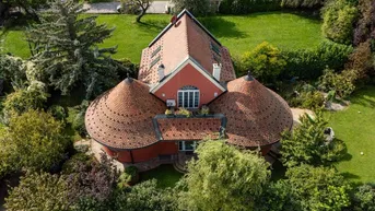 Luftaufnahme eines einzigartigen Hauses mit markanten Rundtürmen und weitläufigem Garten.