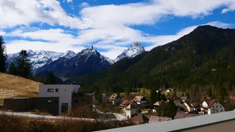 Panoramablick auf schneebedeckte Berge und ein malerisches Dorf in den Alpen.