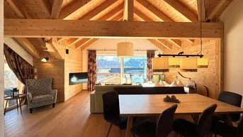 Geräumiger Wohn-Essbereich mit Holzbalkendecke, Parkettboden und Bergblick durch große Fenster.