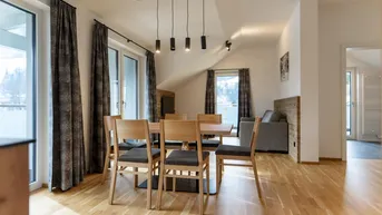 Lichtdurchfluteter Wohn- und Essbereich mit Holzboden und direktem Zugang zum Balkon.