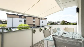 Möblierter Balkon mit Markise, Fliesenboden und Blick auf die Umgebung.