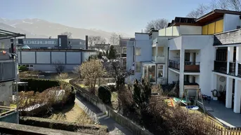 Weitblick vom Balkon auf die umliegenden Gebäude, einen Spielplatz und die Berge im Hintergrund.