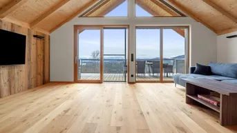Helles Wohnzimmer mit Holzboden, Holzdachschrägen und Zugang zu einem Balkon mit Bergblick.