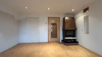 Geräumiges Wohnzimmer mit Holzboden und einem traditionellen Kamin als zentralem Element.