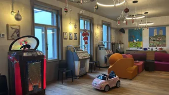 Geräumiges Wohnzimmer mit Holzboden, mehreren Jukeboxen und verspielter Dekoration.
