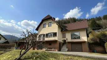 Traditionelles Einfamilienhaus mit Satteldach und Balkon in ländlicher Umgebung mit Bergblick.