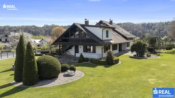 Großzügiges Anwesen mit weitläufigem Rasen und gepflegter Gartenanlage unter blauem Himmel.