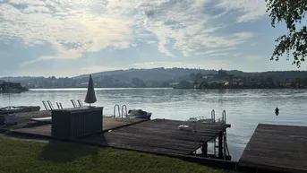 Malerischer Seeblick mit Holzstegen und Booten unter einem sonnigen Himmel.