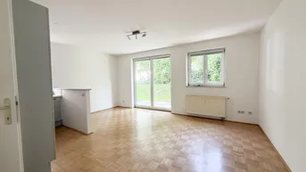 Helles Wohnzimmer mit Parkettboden, Zugang zum Garten und offener Küchenzeile.