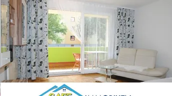 Helles Wohnzimmer mit beigem Sofa, Holzboden und direktem Zugang zu einem sonnigen Balkon mit grüner Brüstung.