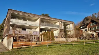Modernes Mehrfamilienhaus mit Holzfassade und Balkonen in grüner Umgebung.