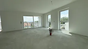 Helles, unfertiges Wohnzimmer mit großen Fenstern, Betonboden und Blick auf die Umgebung.