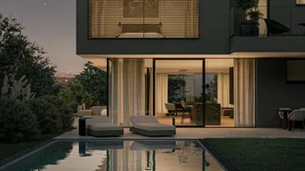 Elegante Poollandschaft mit Liegestühlen und Blick in den beleuchteten Wohnbereich am Abend.