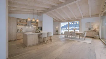 Offene Küche mit Holzschränken und Kücheninsel, Essbereich und Bergblick durch große Fenster.