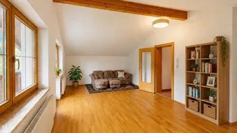 Helles Wohnzimmer mit Holzbalken, Parkettboden und großen Fenstern mit Bergblick.