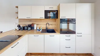 Moderne Einbauküche mit hellen Fronten, Holzarbeitsplatten und integrierten Elektrogeräten.