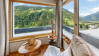 Gemütlicher Wohnbereich mit großen Fenstern und atemberaubendem Blick auf die umliegende Berglandschaft.